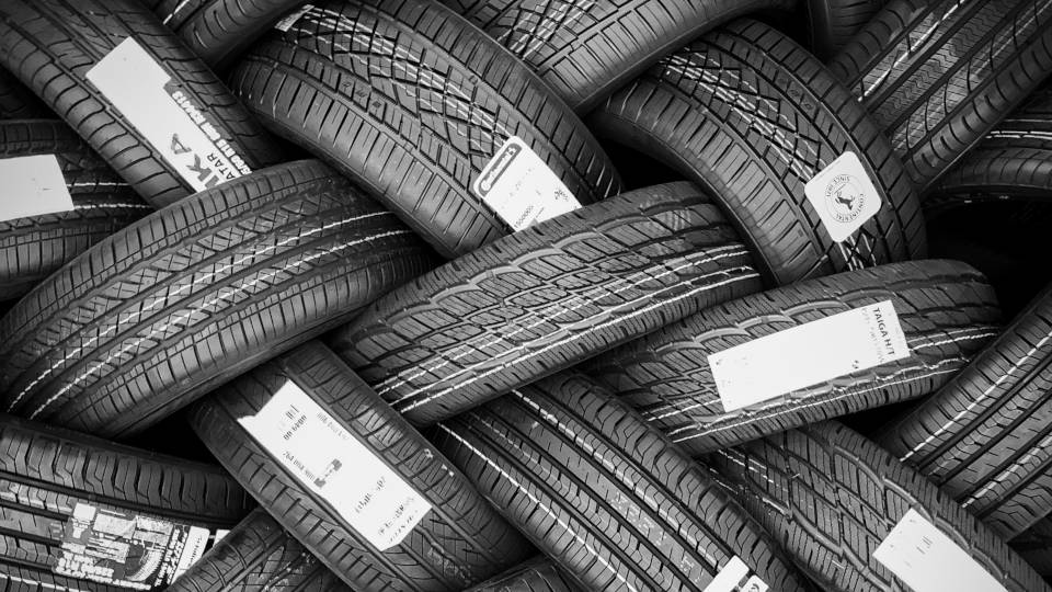 A picture of a pile of brand new tires that are laying criss crossed, looking interconnected.