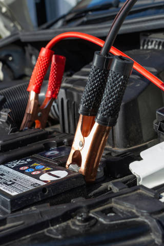 A picture of a car with the hood open, booster cables connected to the car battery.